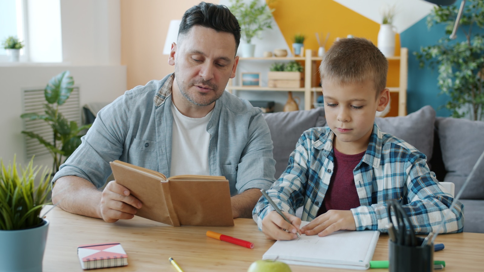 Photo by Vitaly Gariev Father and son reading and writing at table